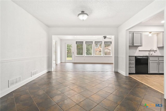 unfurnished living room with sink, a textured ceiling, and ceiling fan