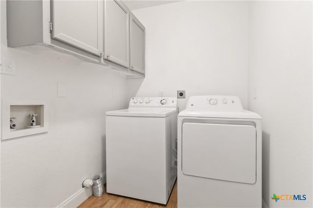 laundry area with electric dryer hookup, washer hookup, light hardwood / wood-style floors, and cabinets