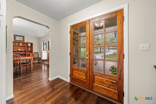 entryway with french doors, dark wood-type flooring, and a textured ceiling