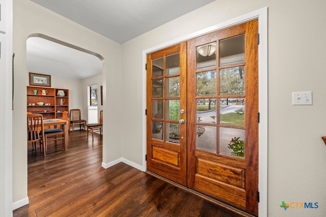 doorway with arched walkways, baseboards, dark wood-style flooring, and french doors