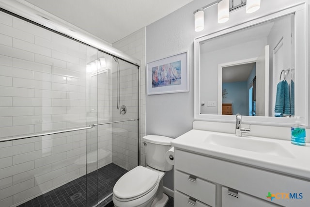 bathroom with toilet, an enclosed shower, and vanity