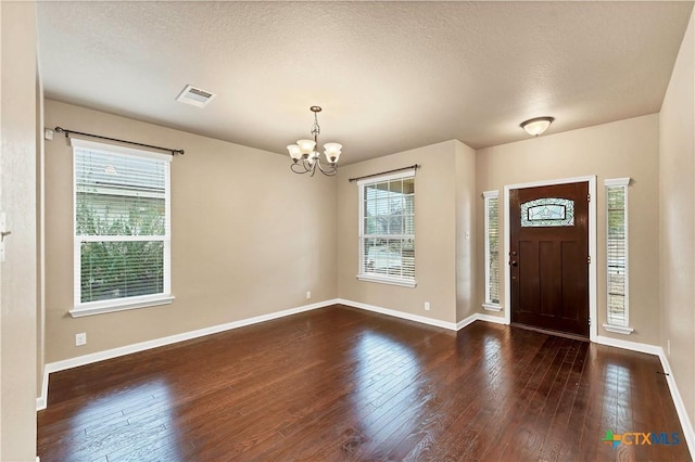 entrance foyer with a notable chandelier, visible vents, and hardwood / wood-style flooring