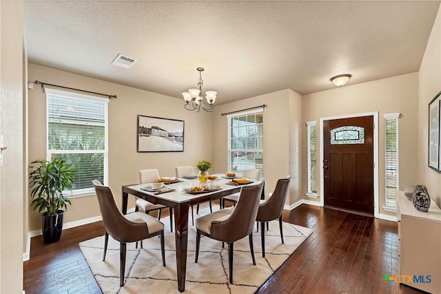 dining room with baseboards, visible vents, an inviting chandelier, hardwood / wood-style flooring, and a textured ceiling