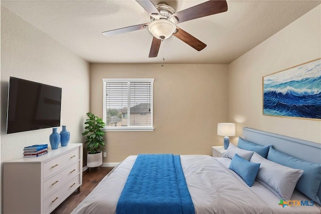 bedroom with a ceiling fan, dark wood-style flooring, and baseboards