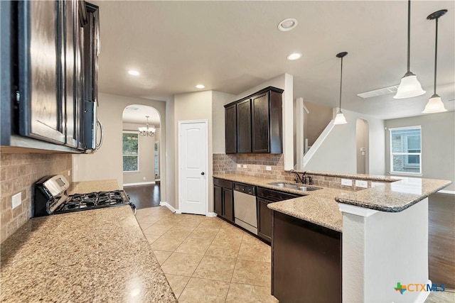 kitchen with dishwasher, light stone counters, arched walkways, gas stove, and a sink