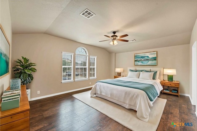 bedroom featuring dark wood finished floors, visible vents, baseboards, and vaulted ceiling