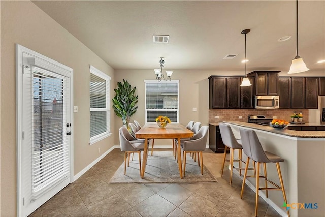 dining space with light tile patterned floors, visible vents, baseboards, and a notable chandelier