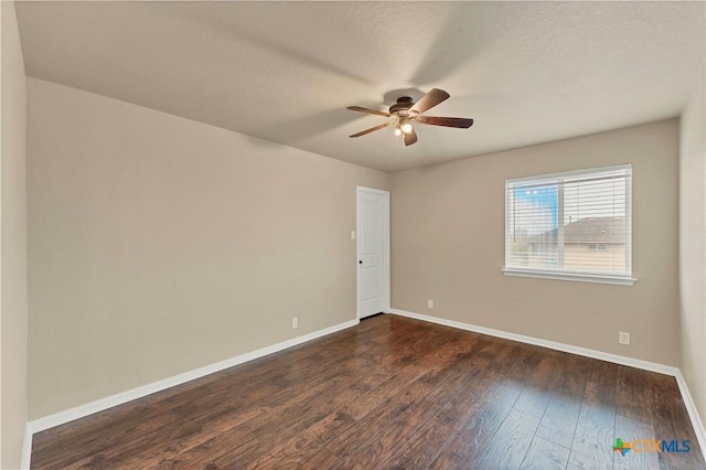 empty room with baseboards, a textured ceiling, dark wood finished floors, and a ceiling fan