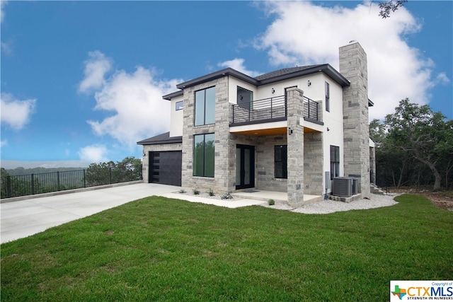 rear view of house with a balcony, a lawn, cooling unit, and a garage