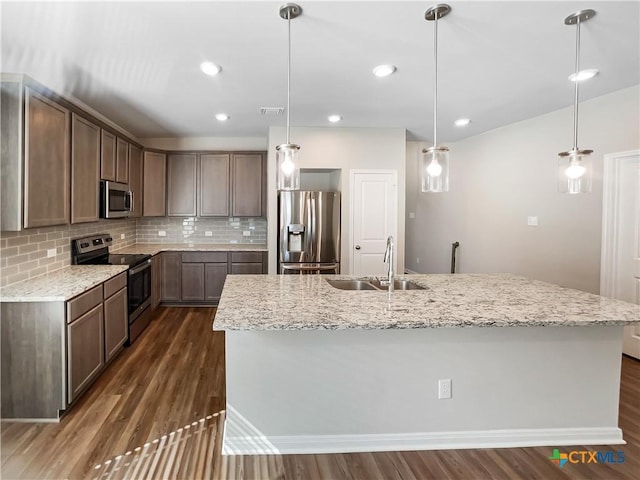 kitchen featuring sink, hanging light fixtures, an island with sink, and appliances with stainless steel finishes