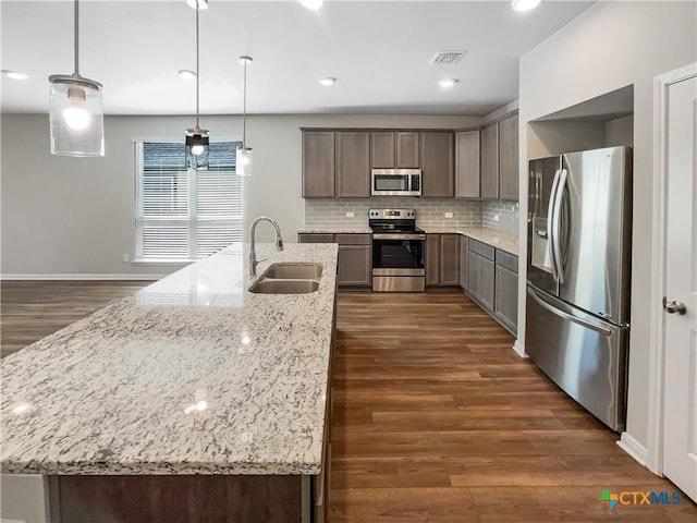 kitchen with sink, hanging light fixtures, stainless steel appliances, tasteful backsplash, and light stone countertops