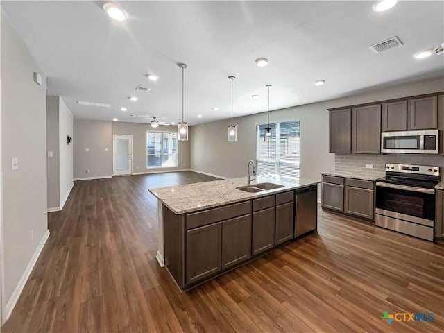 kitchen with decorative light fixtures, sink, decorative backsplash, stainless steel appliances, and light stone countertops