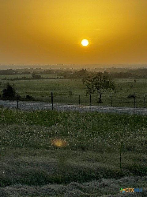 yard at dusk featuring a rural view