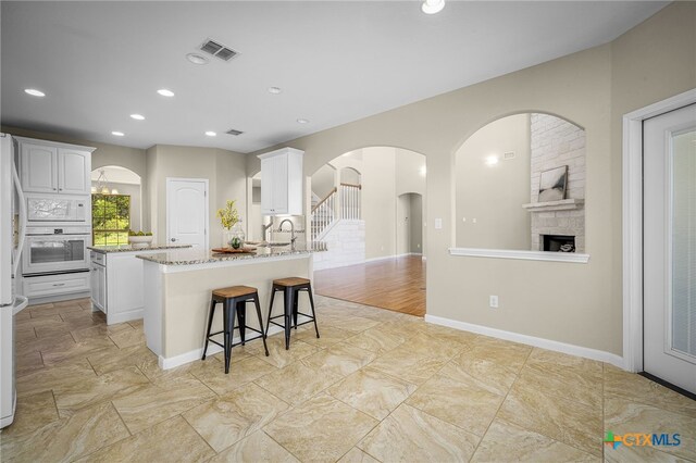 171 Clear Rdg, New Braunfels, TX 78132 - kitchen featuring white cabinets, a kitchen breakfast bar, light stone counters, white appliances, and a peninsula
