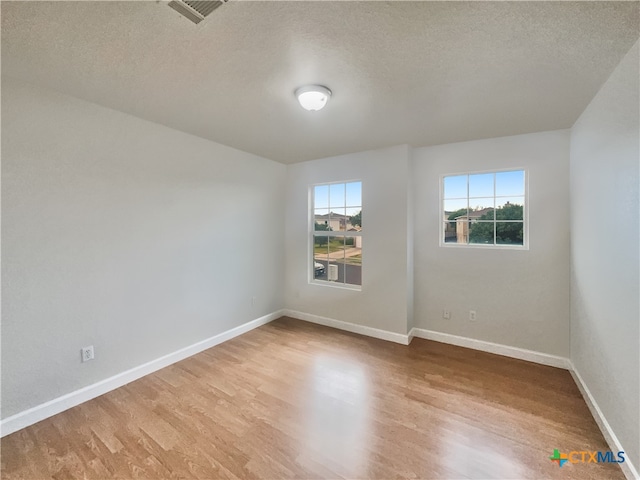 unfurnished room with light hardwood / wood-style floors and a textured ceiling