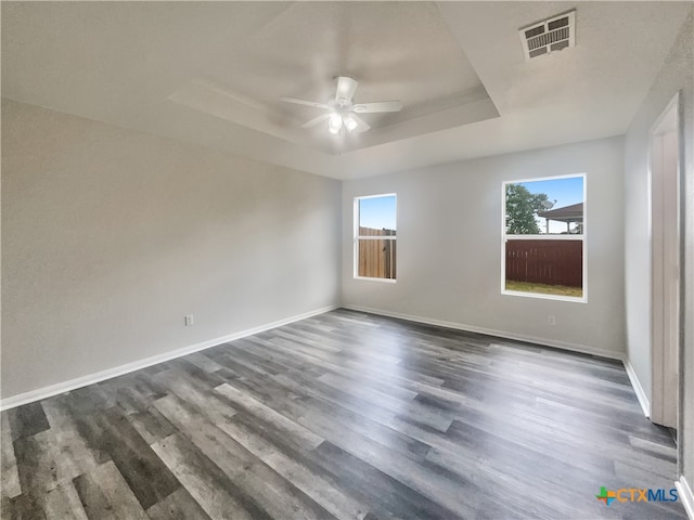 empty room featuring ceiling fan, dark hardwood / wood-style floors, and a raised ceiling