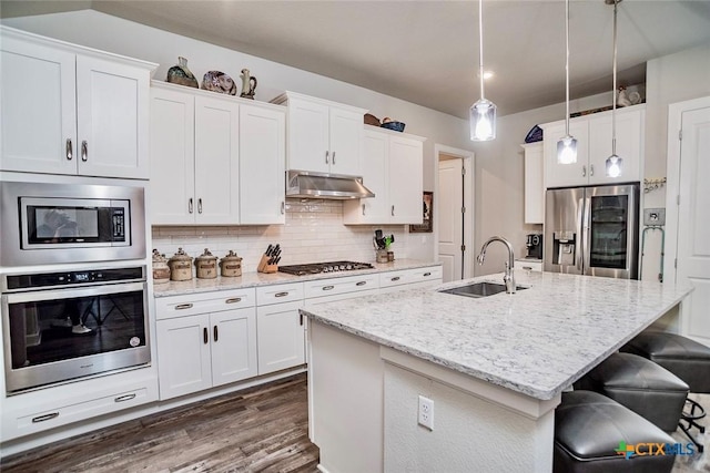 kitchen with appliances with stainless steel finishes, decorative light fixtures, an island with sink, sink, and white cabinets