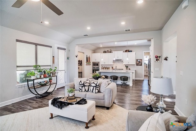 living room with sink, hardwood / wood-style flooring, vaulted ceiling, and ceiling fan