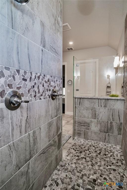 bathroom featuring a tile shower and vaulted ceiling