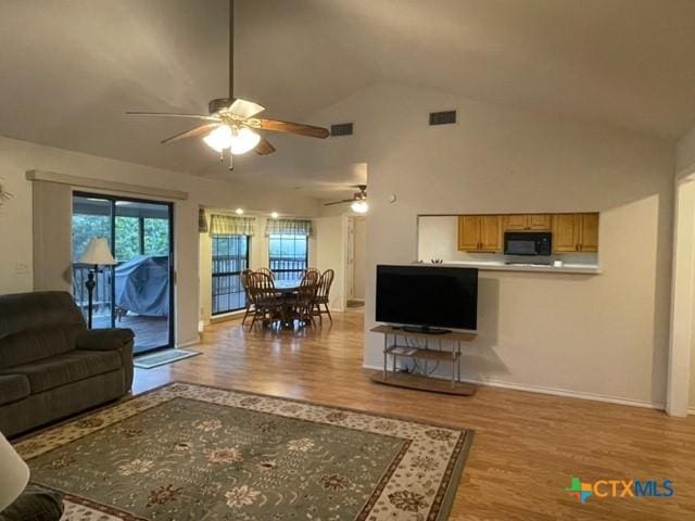 living room featuring light wood-style floors, ceiling fan, visible vents, and high vaulted ceiling