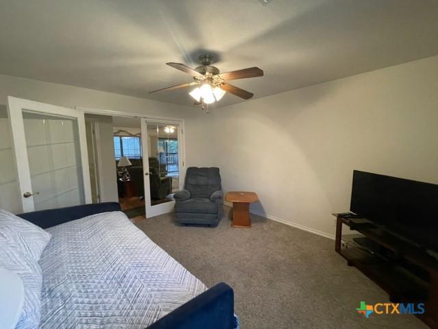 carpeted bedroom with ceiling fan and baseboards