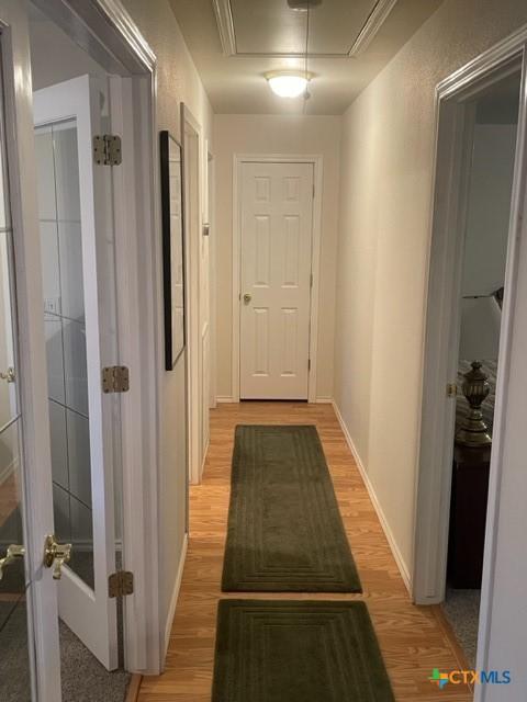 hallway with attic access, french doors, baseboards, and wood finished floors