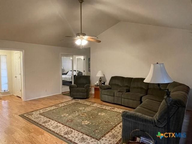 living area with ceiling fan, vaulted ceiling, and wood finished floors