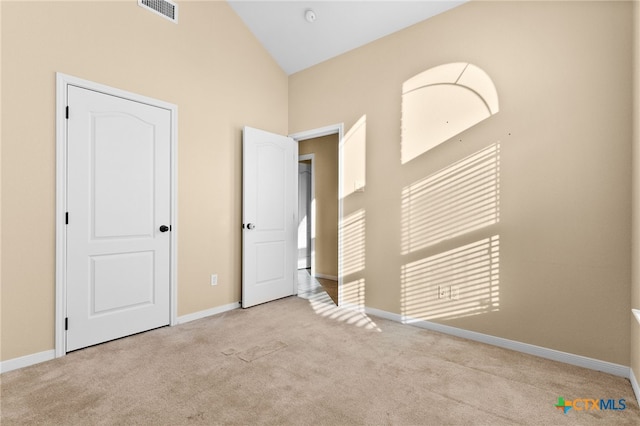 carpeted empty room with high vaulted ceiling