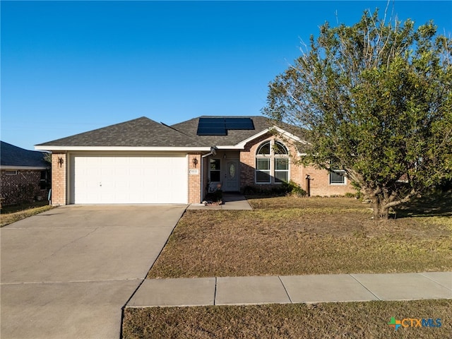 ranch-style house with solar panels, a garage, and a front lawn