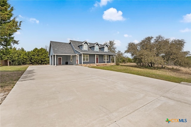 view of front of property with concrete driveway, covered porch, and a front yard