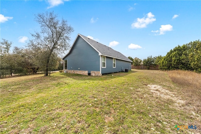 view of side of home with cooling unit, a yard, and fence