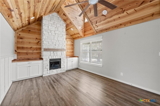 unfurnished living room with wood finished floors, a stone fireplace, lofted ceiling, wood ceiling, and ceiling fan