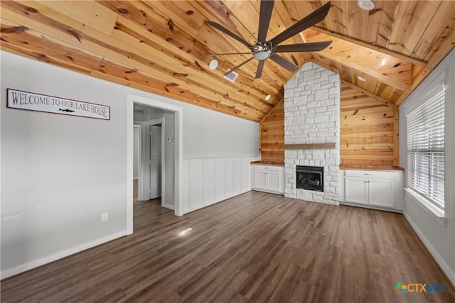 unfurnished living room with a ceiling fan, vaulted ceiling with beams, a stone fireplace, dark wood-type flooring, and wood ceiling