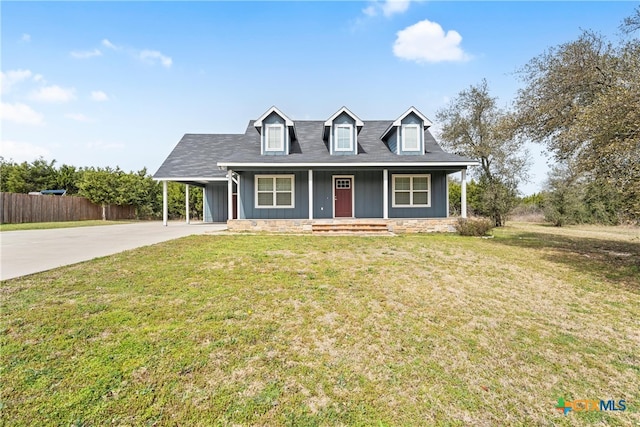 new england style home with an attached carport, concrete driveway, fence, and a front lawn