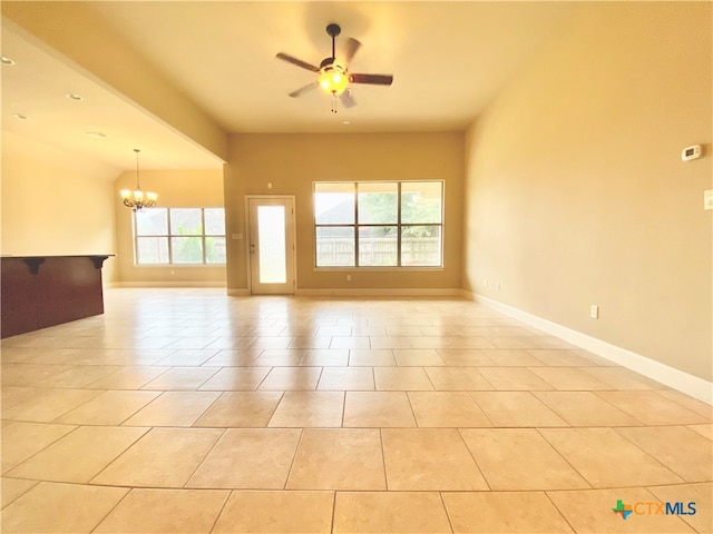 tiled empty room featuring ceiling fan with notable chandelier and a healthy amount of sunlight