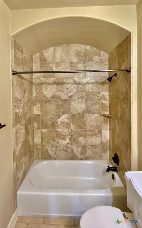 bathroom featuring tile patterned flooring, toilet, and tiled shower / bath combo