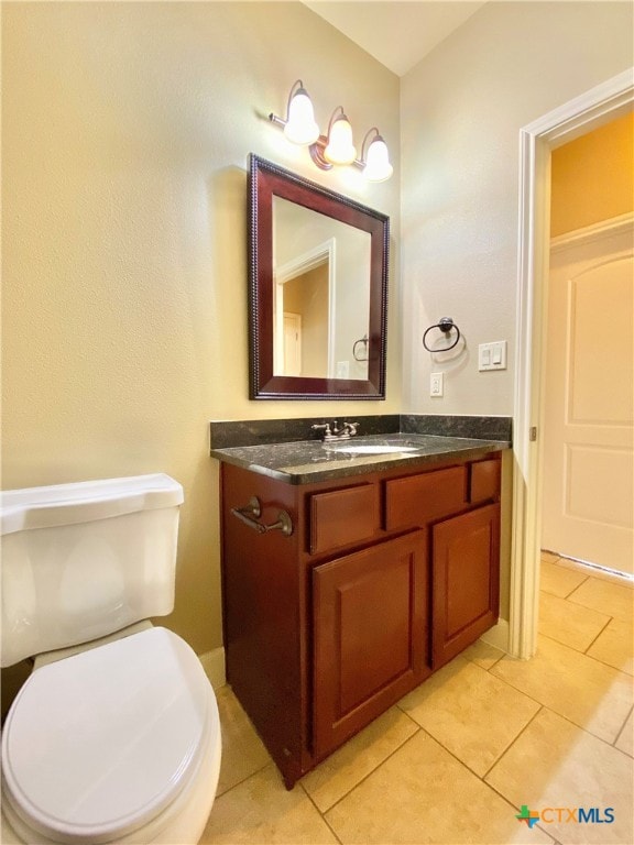 bathroom with toilet, vanity, and tile patterned floors