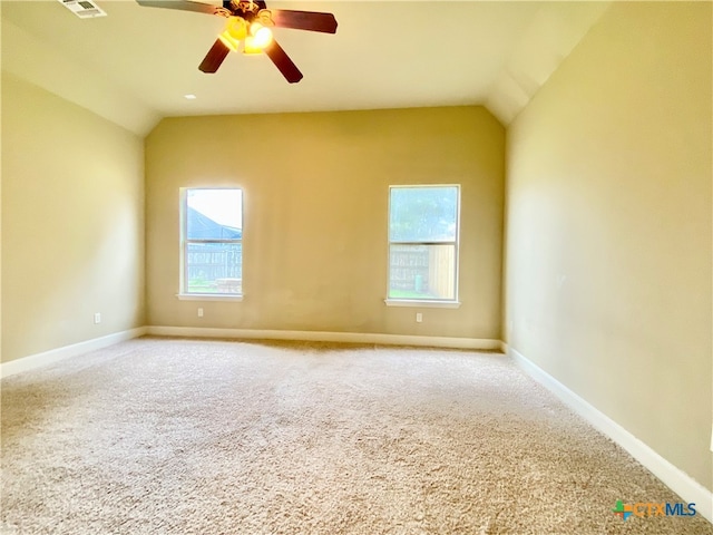 carpeted empty room featuring ceiling fan, plenty of natural light, and lofted ceiling