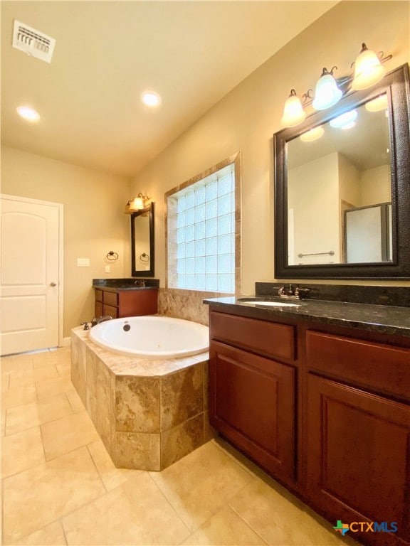 bathroom with vanity, tile patterned floors, and a relaxing tiled tub