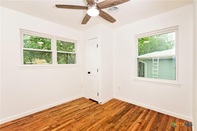 spare room featuring baseboards, a ceiling fan, wood finished floors, and visible vents