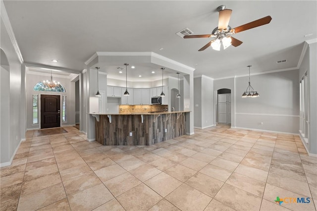 5905 Turtle Creek Trl, Temple, TX 76502 - kitchen featuring arched walkways, ornamental molding, a chandelier, stainless steel microwave, and decorative backsplash