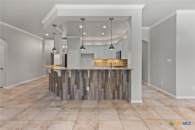 5905 Turtle Creek Trl, Temple, TX 76502 - kitchen featuring crown molding, light stone countertops, backsplash, arched walkways, and recessed lighting