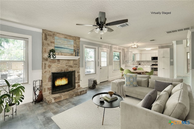 1506 Spiderlily Vw, Cedar Park, TX 78613 - living area with ornamental molding, a textured ceiling, plenty of natural light, ceiling fan, and a fireplace