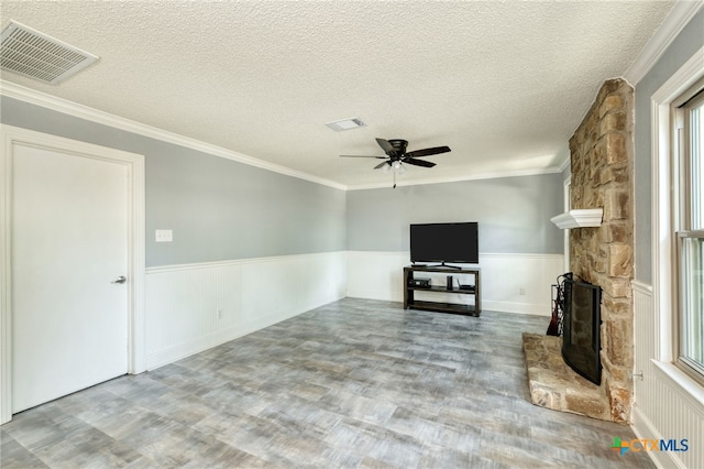 1506 Spiderlily Vw, Cedar Park, TX 78613 - unfurnished living room with wood finished floors, a wainscoted wall, a ceiling fan, a textured ceiling, and a stone fireplace