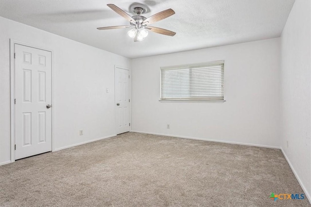 carpeted empty room featuring ceiling fan and baseboards