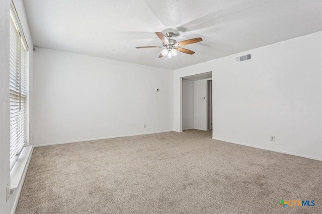 carpeted empty room with a ceiling fan, plenty of natural light, and baseboards