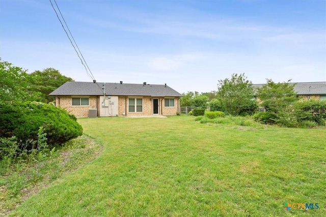 back of house with a lawn, central AC unit, and brick siding