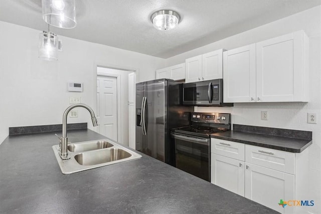 kitchen with stainless steel appliances, a sink, dark countertops, white cabinetry, and decorative light fixtures