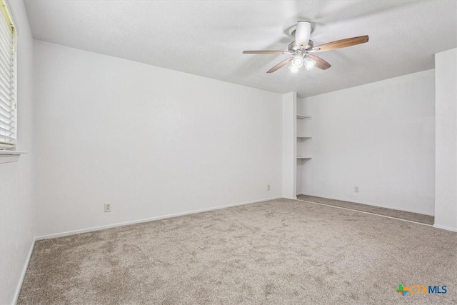 empty room featuring a ceiling fan, carpet, and baseboards