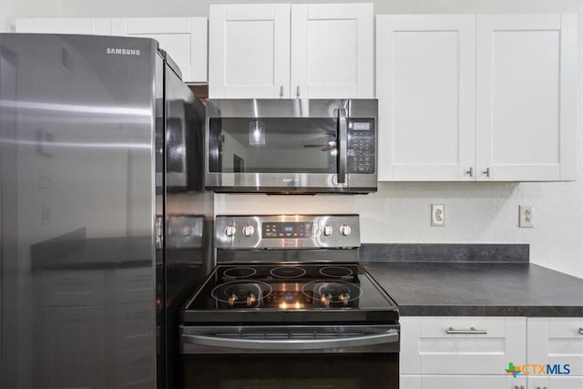kitchen with appliances with stainless steel finishes, dark countertops, and white cabinetry